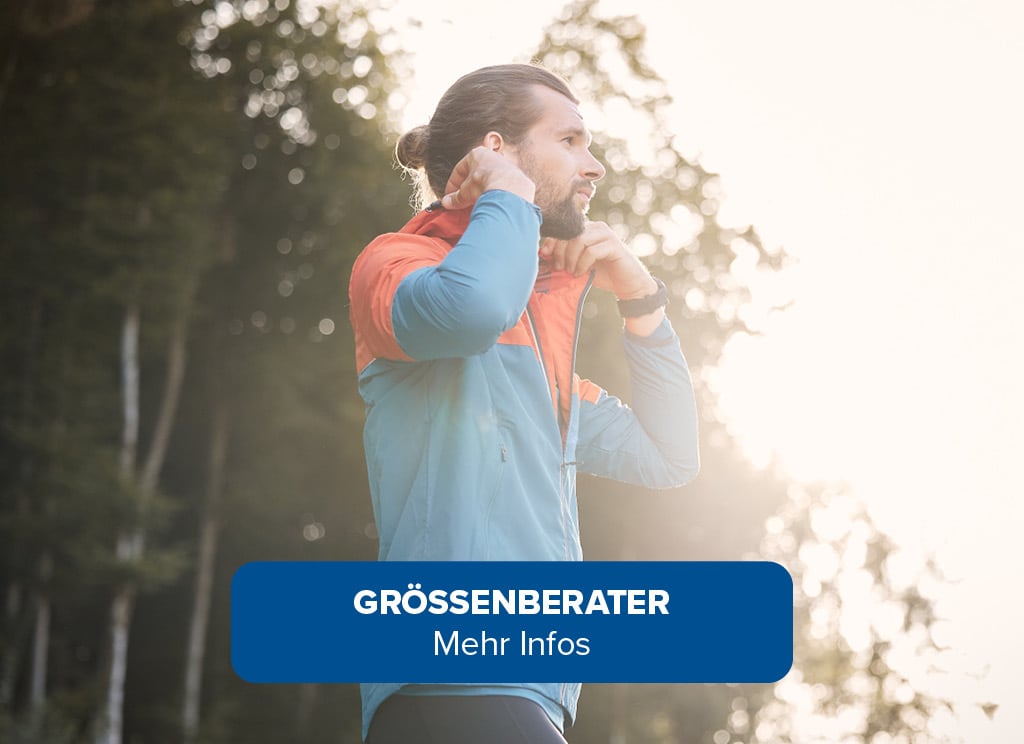 Das Bild zeigt eine Person im Freien, die eine blau-orange Jacke trägt. Im Hintergrund sind Bäume zu sehen. Am unteren Rand des Bildes befindet sich ein blaues Banner mit weißem Text, der lautet: Größenberater. Mehr Infos