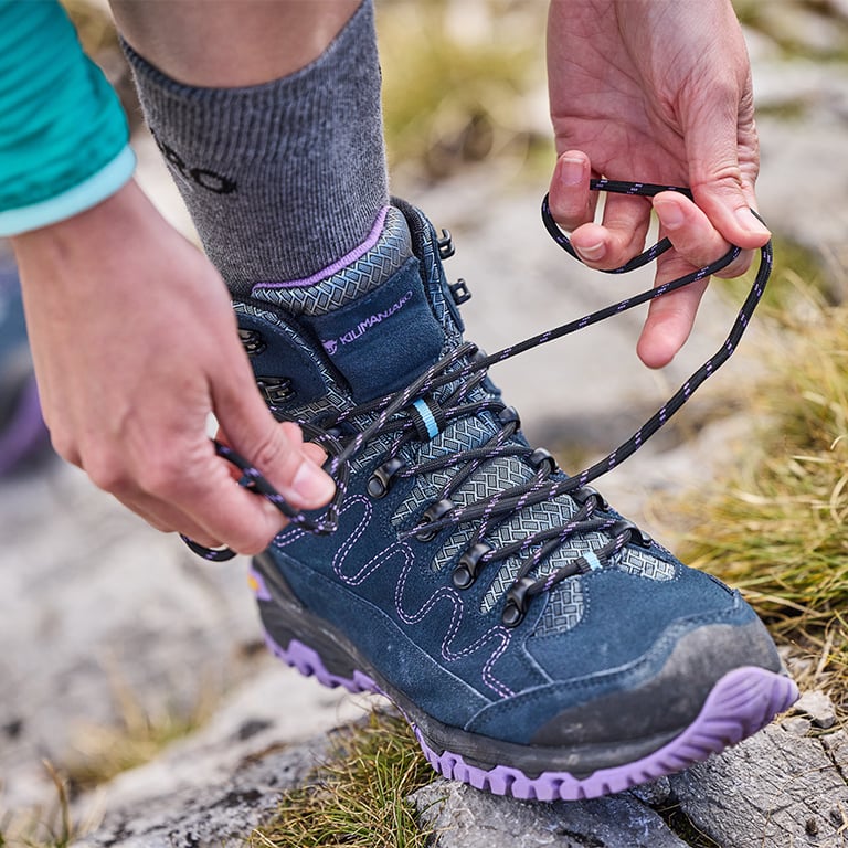 Eine Person schnürt ihre Wanderschuhe.