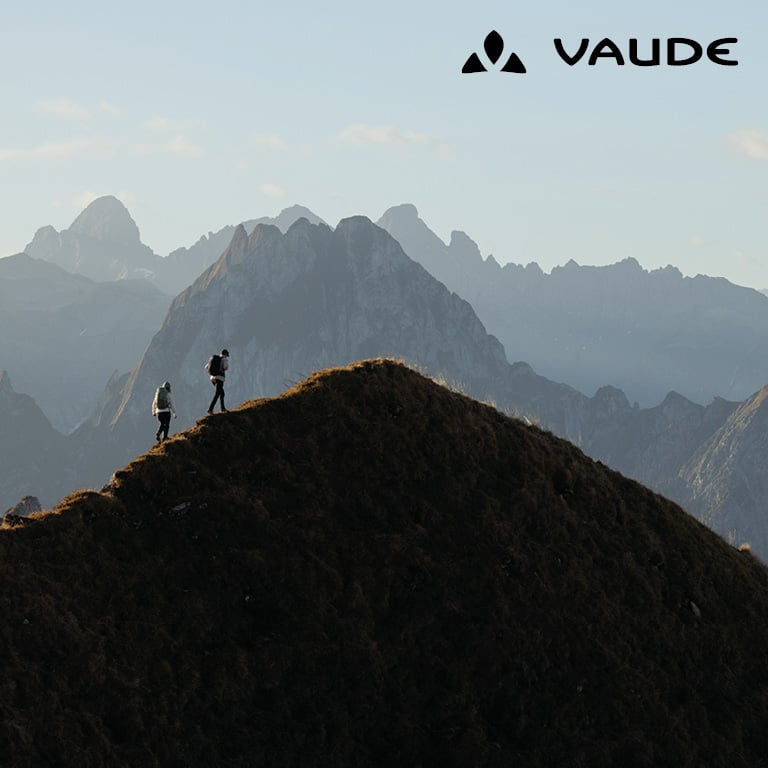 Marke Vaude 2 Wanderer stehen auf dem Gipfel eines Berges bei düsterem Wetter
