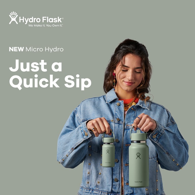 Eine Person hält zwei grüne Hydro‑Flask‑Trinkflaschen vor einer graugrünen Hintergrundfläche, daneben steht der Text „NEW Micro Hydro – Just a Quick Sip“.