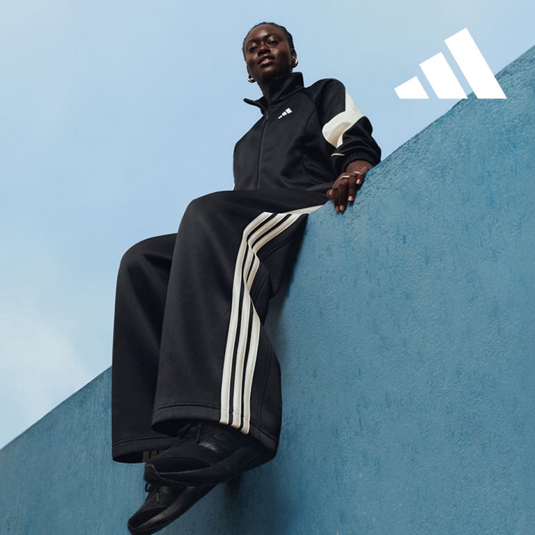Eine Person in schwarzer Sportkleidung mit weißen Streifen sitzt auf einer erhöhten blauen Fläche. Der Hintergrund besteht aus einem hellblauen Himmel, oben rechts im Bild ist das adidas Logo zu sehen.