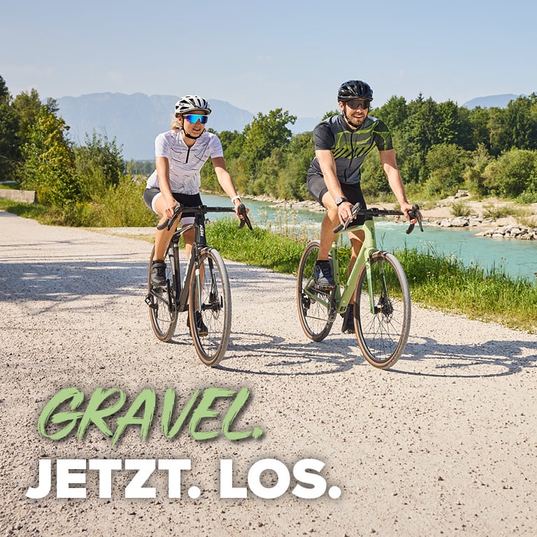 Gravel. Jetzt. Los. 2 Personen fahren mit einem Gravel Bike an einem Radweg.