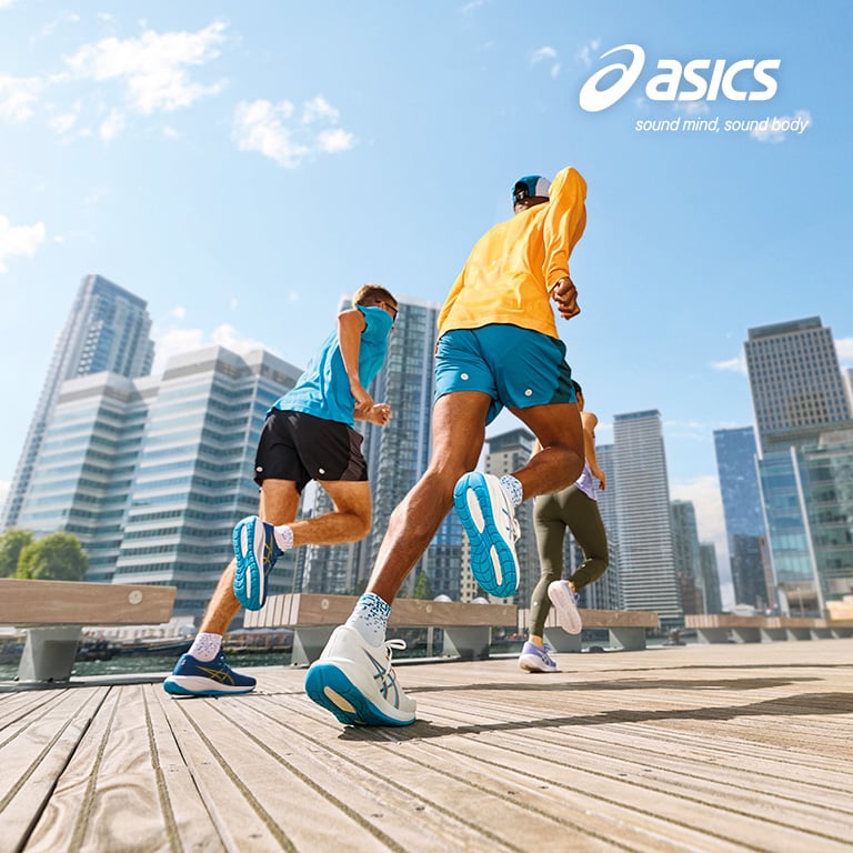 Mehrere Personen laufen auf einer breiten Holzpromenade entlang eines Gewässers. Die Personen tragen sportliche Kleidung und Laufschuhe. Rechts oben im Bild ist das ASICS‑Logo mit dem Slogan „sound mind, sound body“ zu sehen.