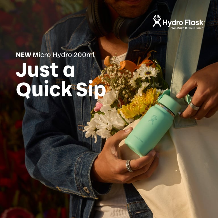 Mintgrüne Hydro Flask Micro (200 ml) wird aus einer Tasche neben einem bunten Blumenstrauß gehalten; Werbetext „Just a Quick Sip“ und Produktname sind im Bild eingeblendet.