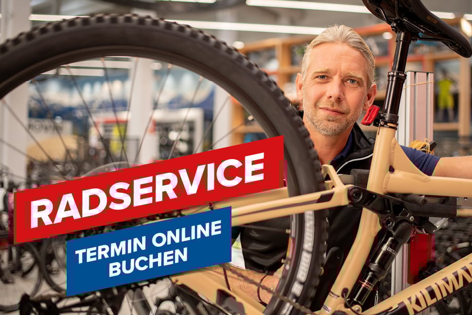 Eine Person arbeitet an einem Fahrrad in einer Werkstatt. Im Bild ist Text zu sehen: Eine Person arbeitet an einem Fahrrad in einer Werkstatt. Im Bild ist Text zu sehen: