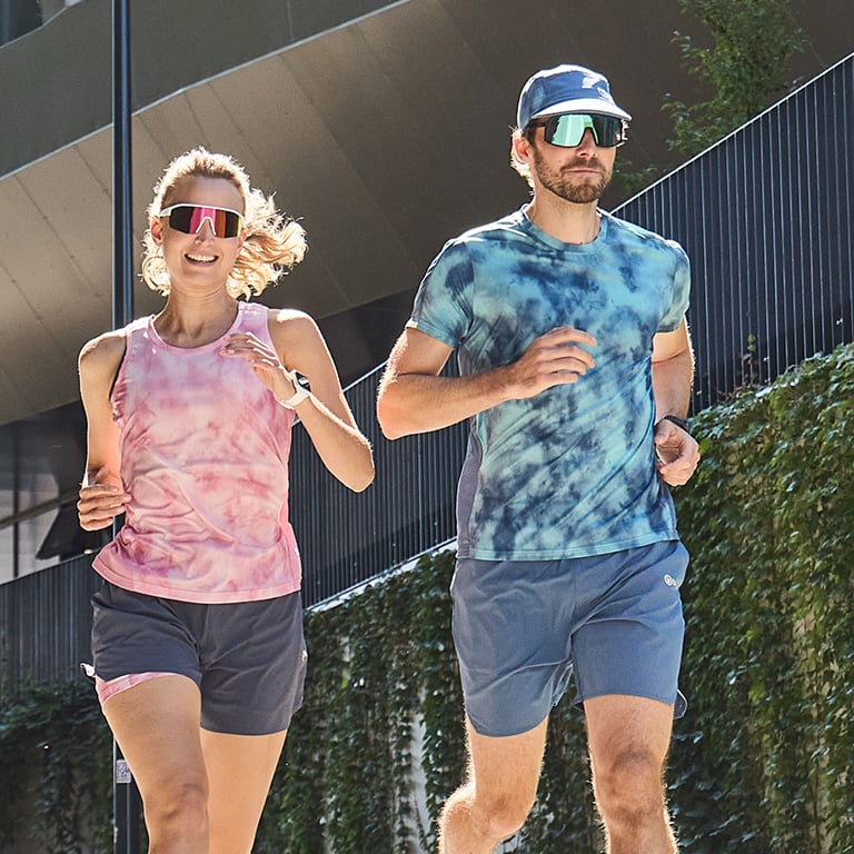 Zwei Personen in Laufbekleidung joggen in der Stadt.