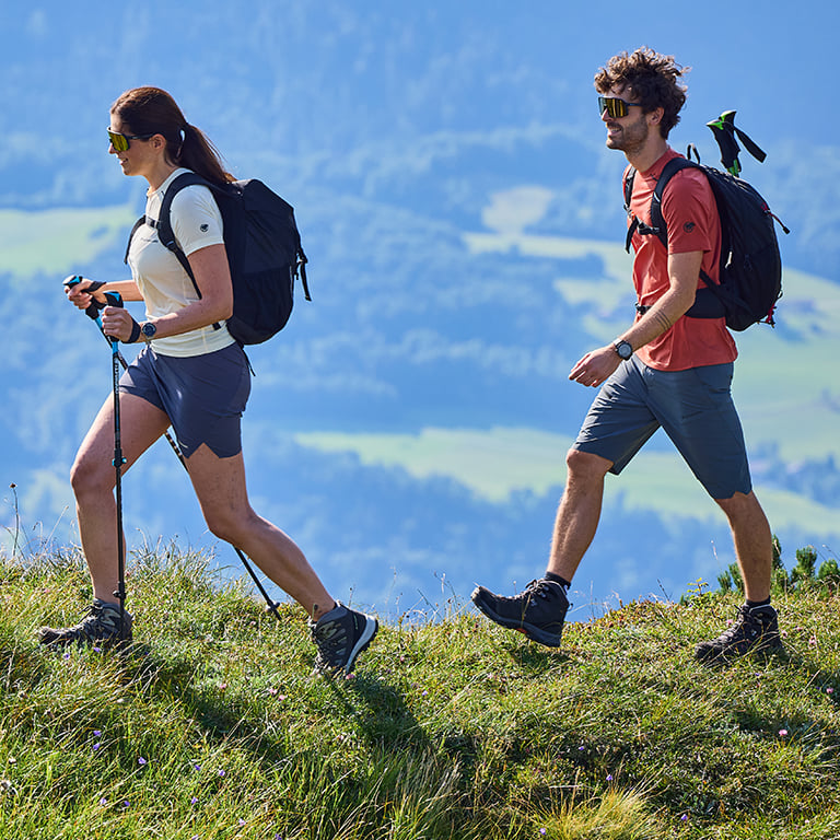 Zwei Personen in Wanderkleidung wandern in den Bergen.