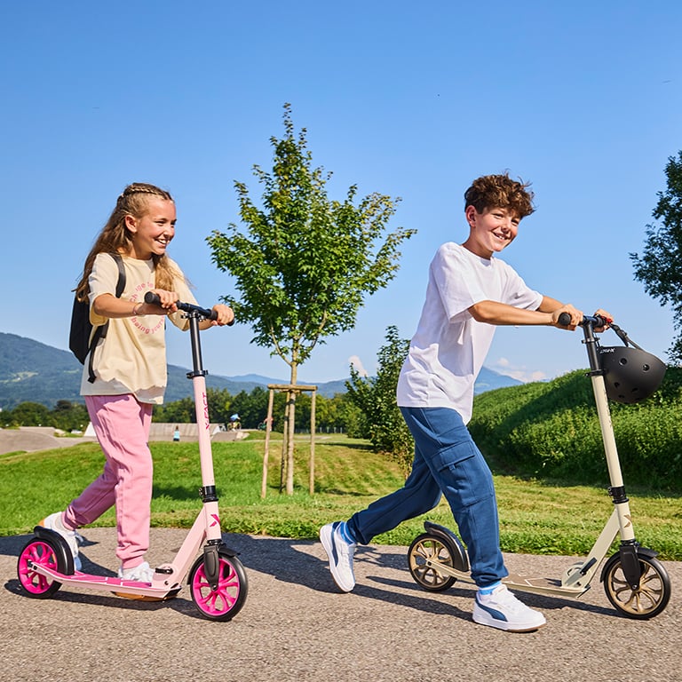 Zwei Kinder fahren mit Scootern.