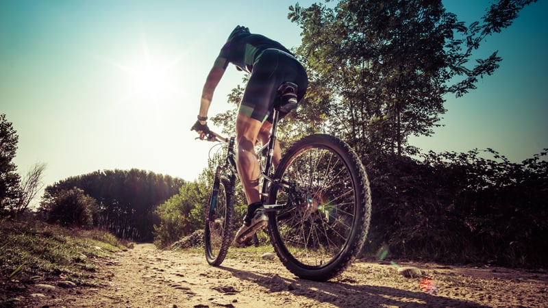 Ein Mann fährt auf einem Mountainbike. Man sieht ihn von hinten. Der Fokus ist auf seine Radhose.