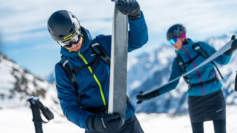 Ein Mann und eine Frau ziehen nach einer Skitour die Steigfelle von ihren Skiern ab.