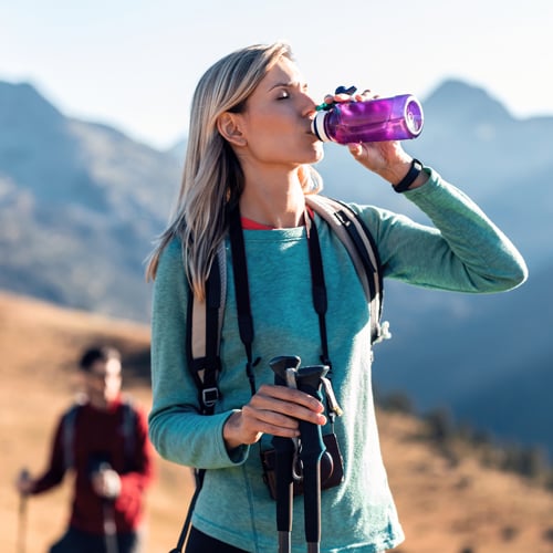 Wanderer trinkt im Gebirge, im Hintergrund ist eine zweite Person