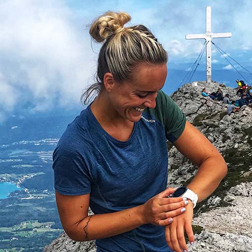 Beitragsbild zu Blogeintrag: Suunto 5 im Hervis Community-Test Frau neben Gipfelkreuz