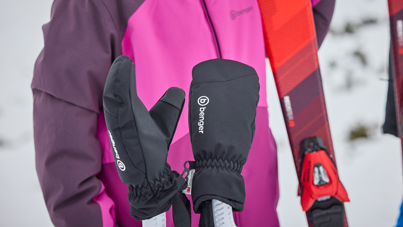 Nasse Handschuhe richtig trocknen Ein Paar schwarze LEKI-Skihandschuhe liegt nebeneinander auf einem grauen Handtuch, ausgebreitet auf einem Holzboden zum Trocknen nach dem Einsatz.