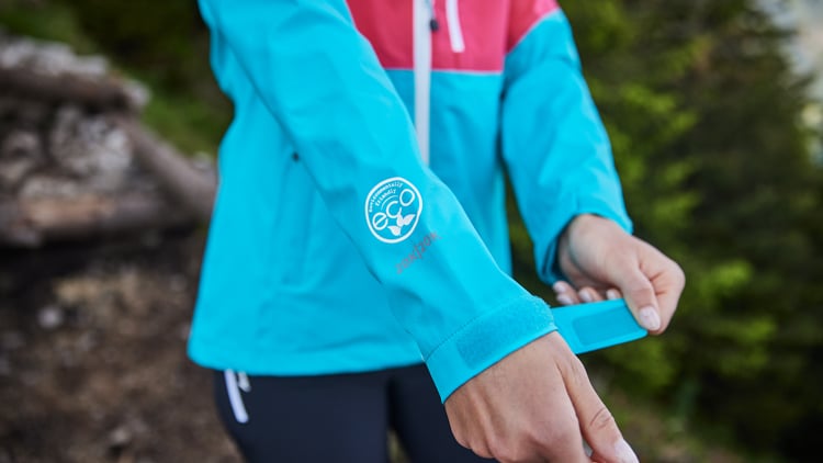 Person mit blauer Regenjacke in der Natur