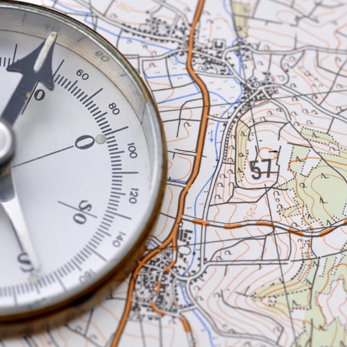 Kompass auf einer topografischen Karte mit Höhenlinien und geografischen Details.