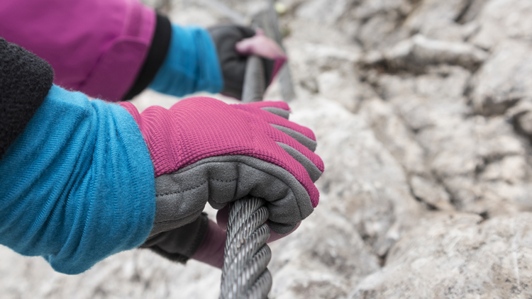 Nahaufnahme von  behandschuhten Händen die sich an einem Kletterseil festhalten