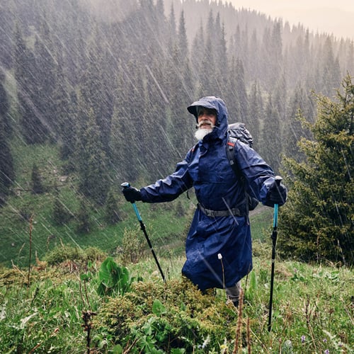 Person wandert bei starkem Regen in der Natur