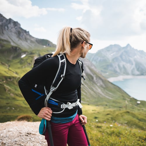 Wanderer mit Rucksack auf Bergpfad mit Blick auf Hügel und See