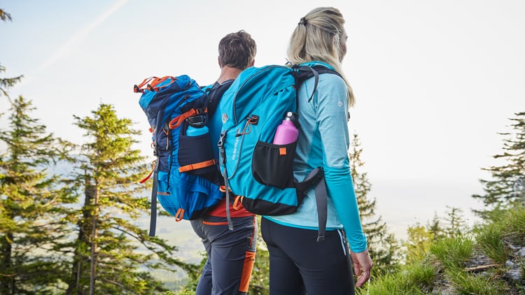 Outdoorberater Mann und Frau wandern mit großen Rucksäcken durch eine bewaldete Landschaft