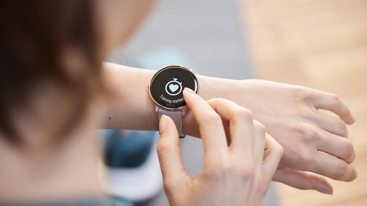 Nahaufnahme einer Person, die mit einer Smartwatch am Handgelenk interagiert. Auf dem Display ist ein Stoppuhr-Symbol und der Text ‚Activity stopped‘ zu sehen
