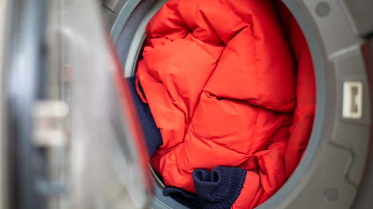 Nahaufnahme des Inneren einer Waschmaschine mit einer roten Daunenjacke darin