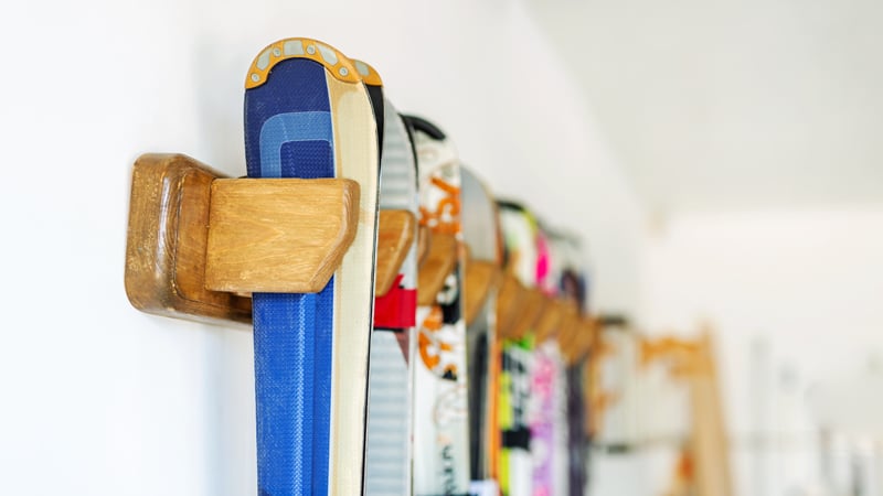 Mehrere Paar Ski hängen ordentlich in einer Wandhalterung.